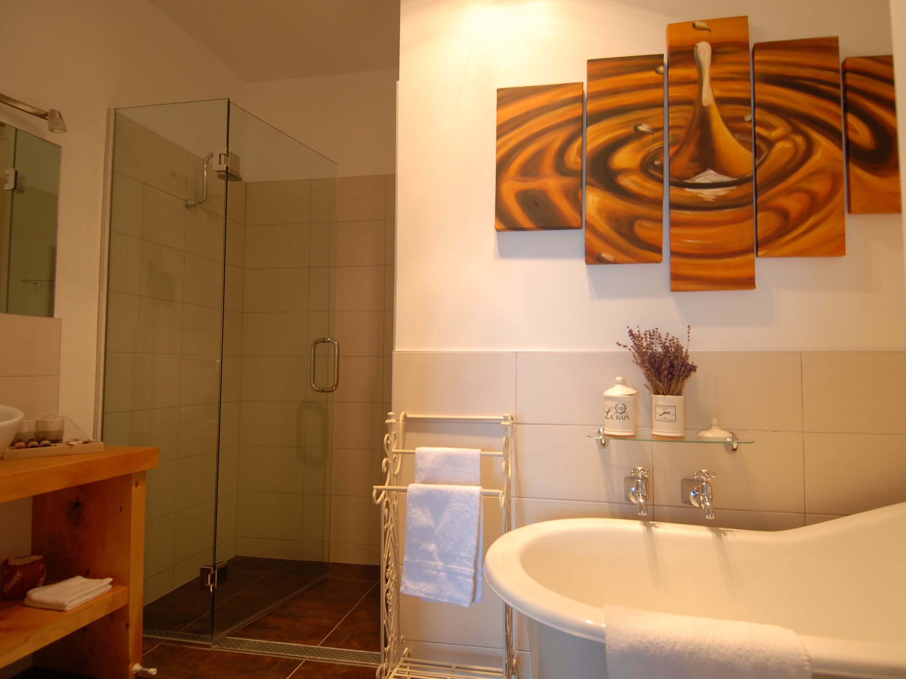 Un baño moderno con cabina de ducha de vidrio, una bañera independiente y un estante empotrado con artículos de aseo.
