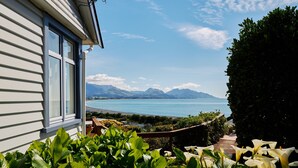 A house with a view of a calm sea and mountains.