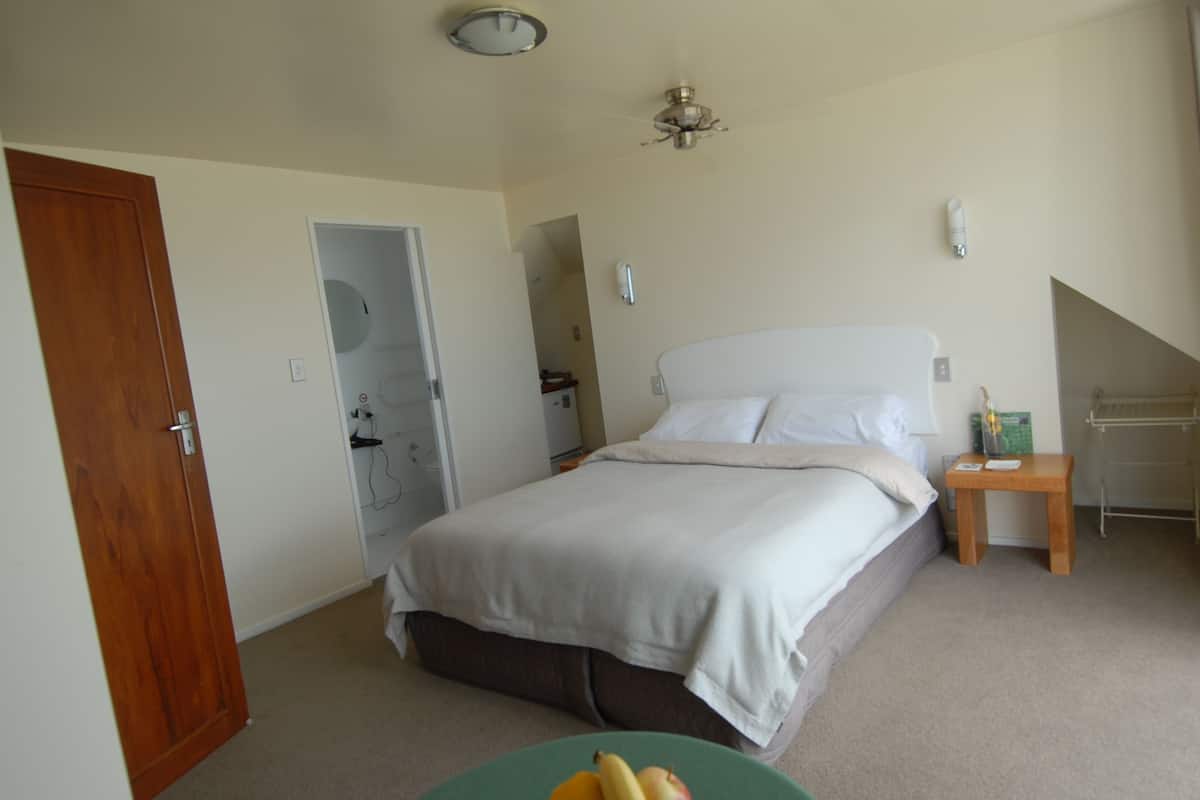 A bedroom with a bed, bedside table, and a ceiling fan.