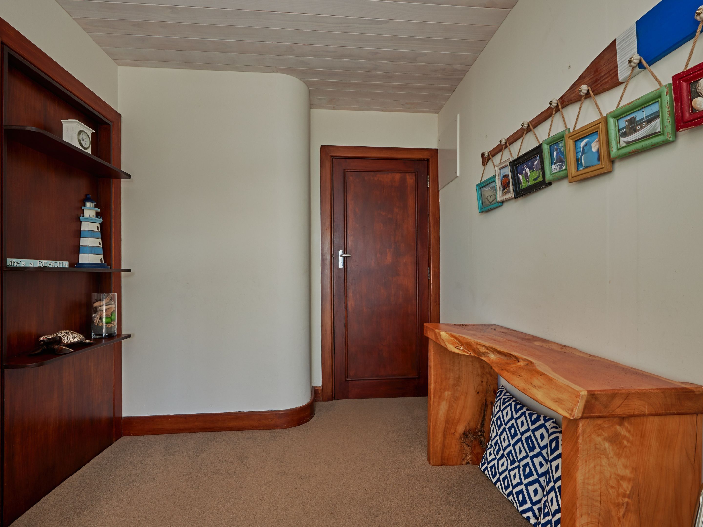 A hallway with a wooden bench, a door, and a wall with framed pictures.