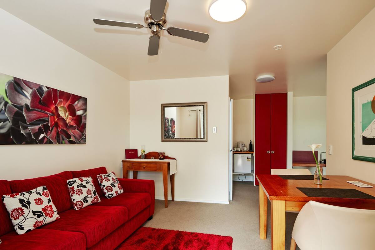 A modern living room with a red sofa, a wooden coffee table, and a ceiling fan.
