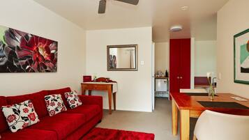 A modern living room with a red sofa, a wooden coffee table, and a ceiling fan.