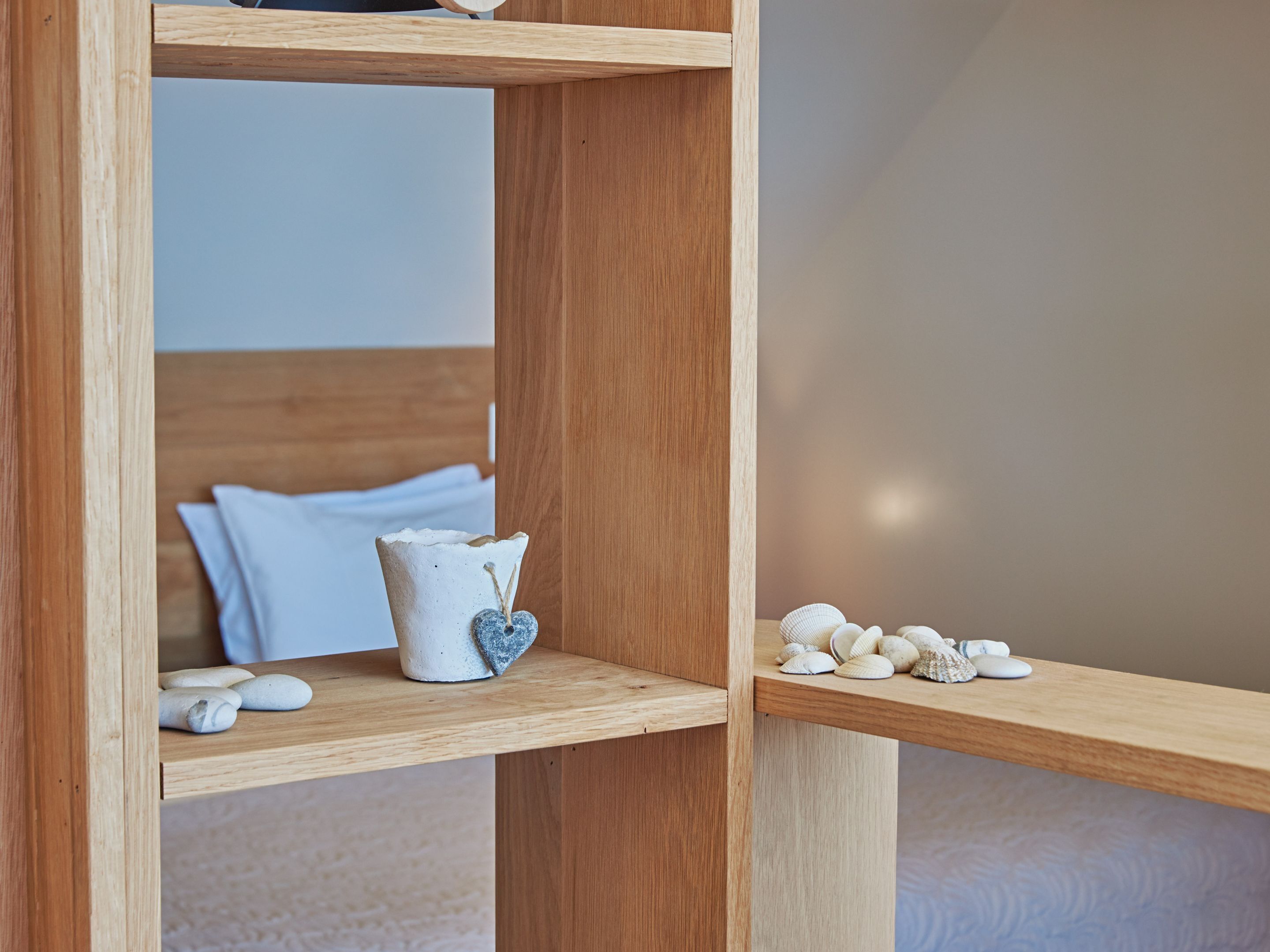 A wooden shelf with a ceramic pot and seashells.
