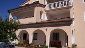 A two-story building with a balcony, arched windows, and a paved entrance area with potted plants. - Apartment in Umag with WIFI (853-2) (Umag)