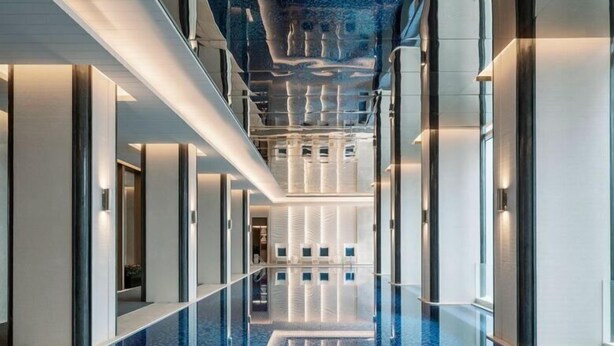 Un pasillo moderno de hotel con una piscina reflectante.