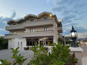 A multi-story hotel with a flat roof, balconies, and a ground-level restaurant area. - Hotel Holiday (Podgorica)