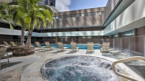 A rooftop pool area with lounge chairs, a hot tub, and a palm tree. - Downtown Honolulu Suite Near Ala Moana Beach! (Honolulu)