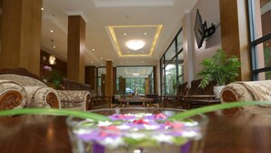 A lobby with a central table, seating areas, and large windows. - Grand Garden Hotel Yangon (Yangon)