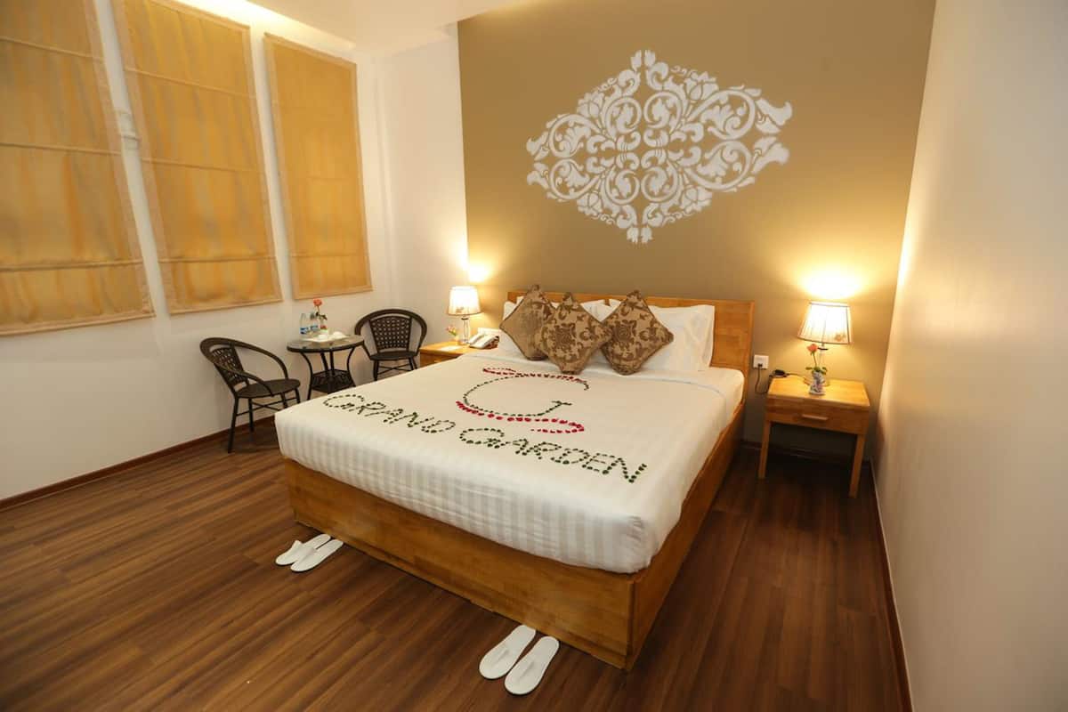 A hotel room with a bed, two chairs, a small table, and a nightstand.