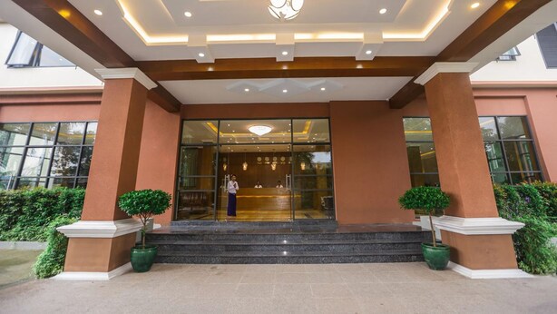 A hotel entrance with a modern design, featuring a reception desk, glass doors, and a decorative ceiling light. - Grand Garden Hotel Yangon (Yangon)