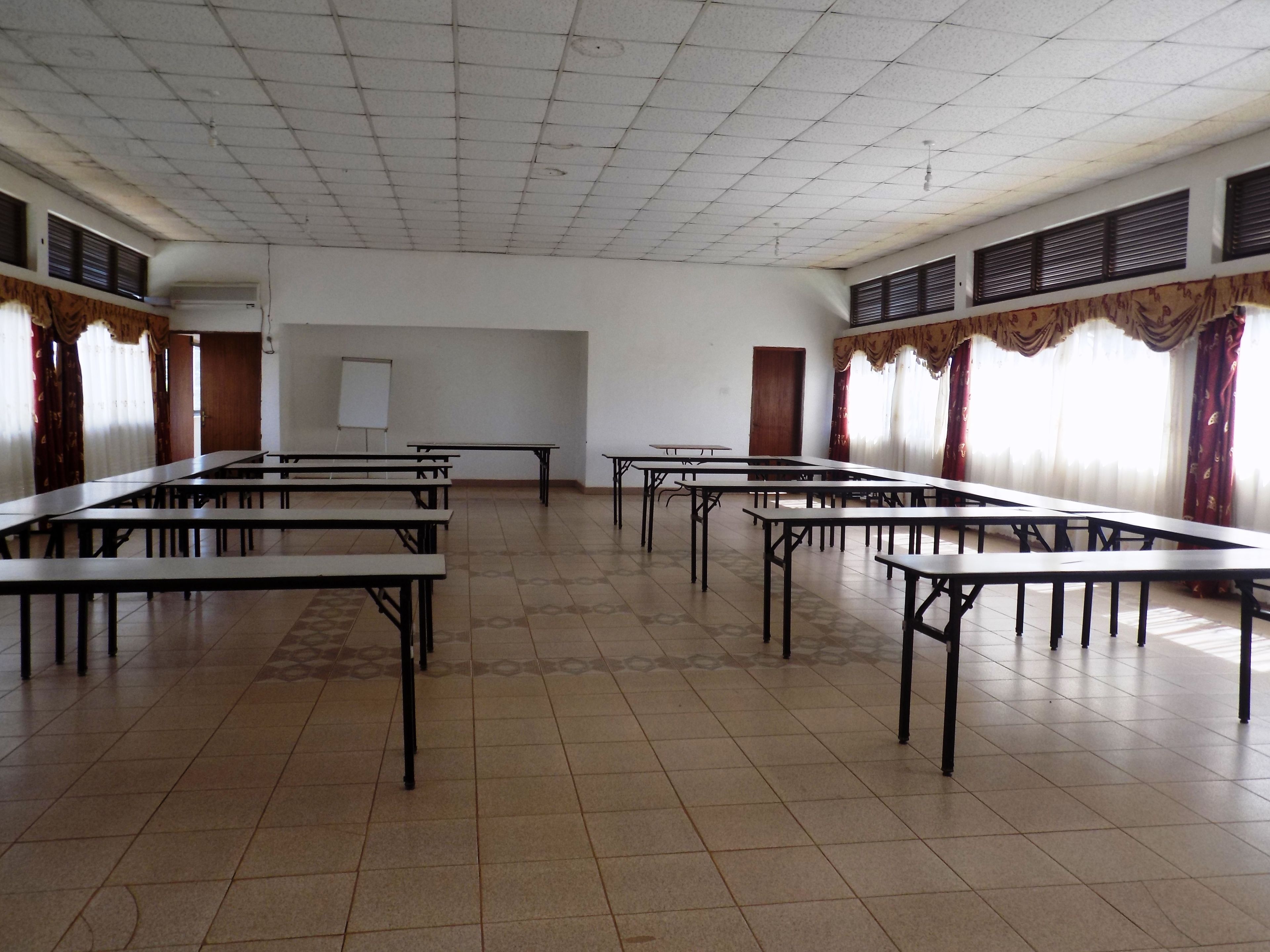 A large, empty conference room with long tables and a whiteboard.