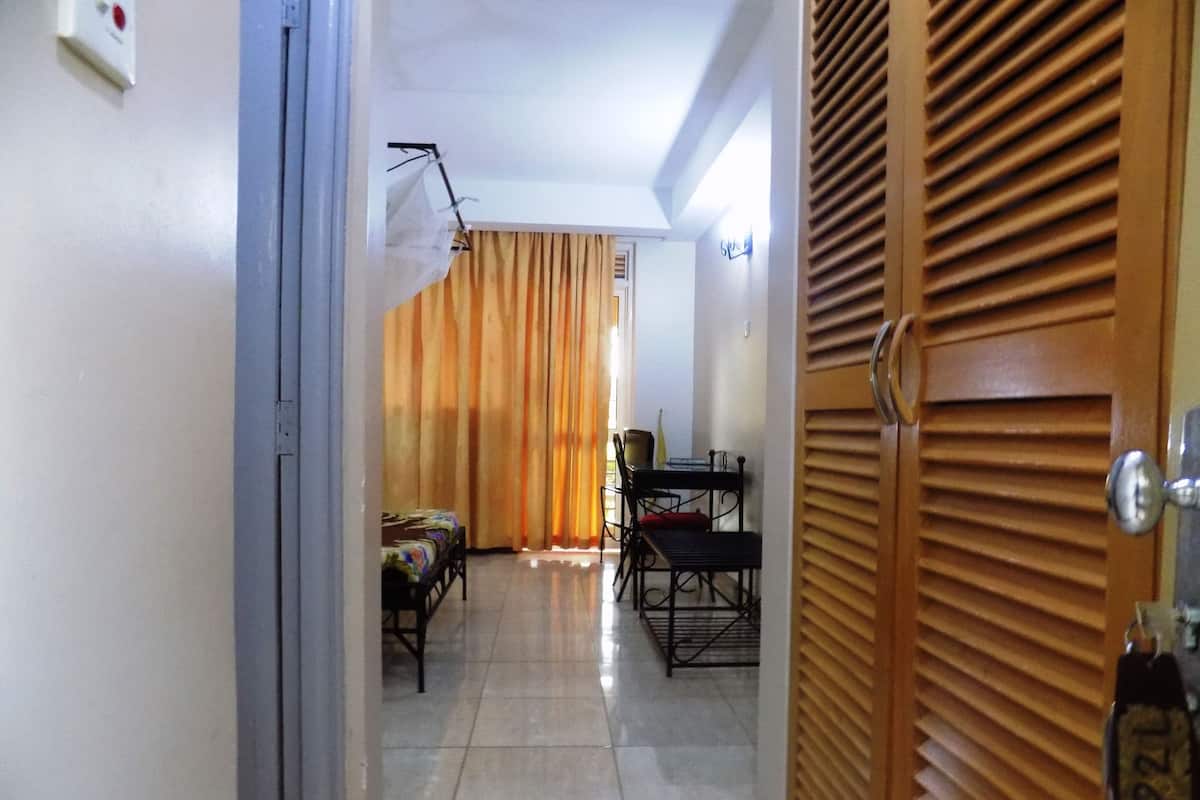 A hallway leading to a dining area with a table and chairs, a bed, and a door with a keychain.