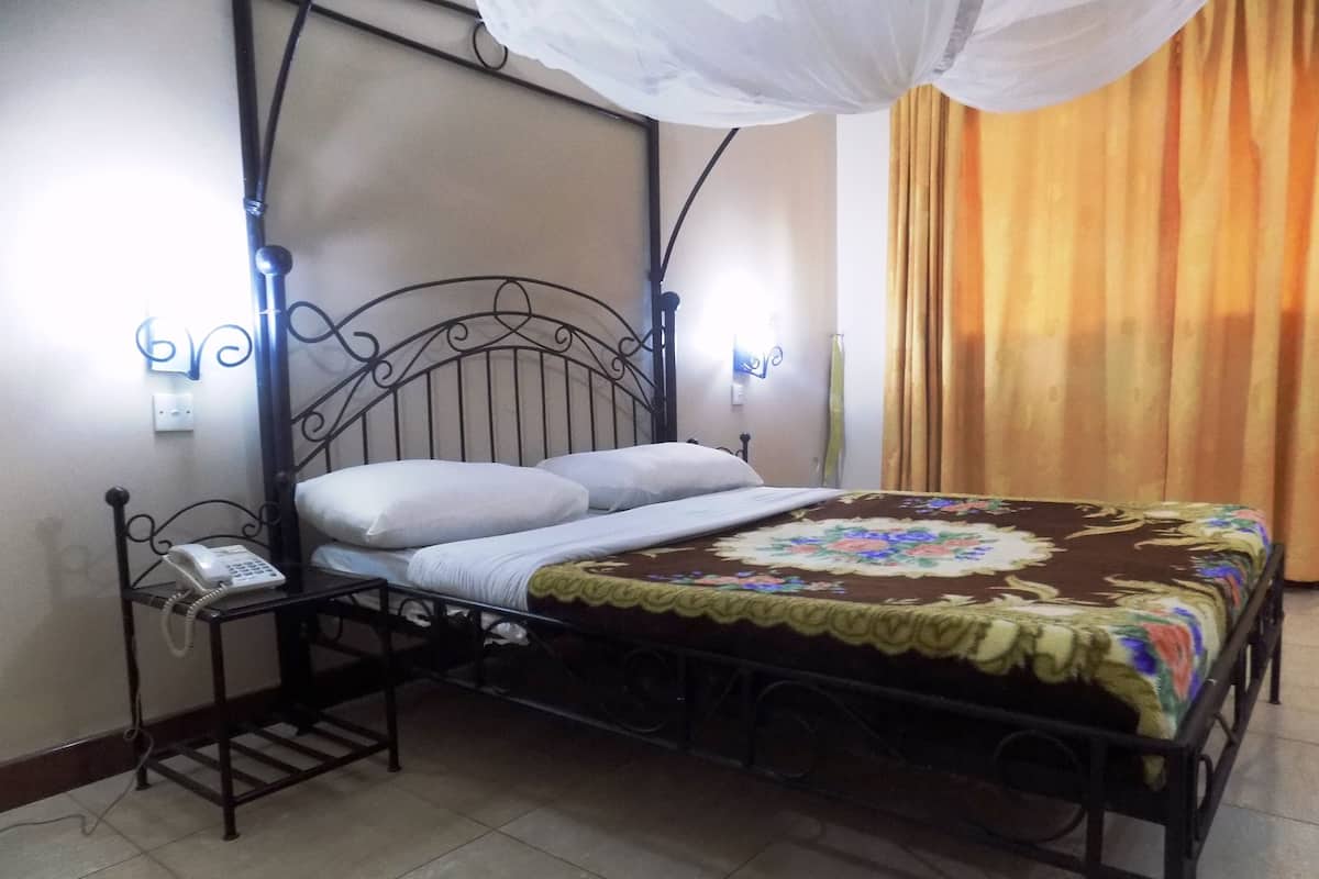 A bed with a canopy, a bedside telephone, and a wall-mounted light fixture.