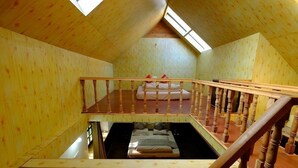 Interior de madeira com quarto em mezanino, escada e claraboia.