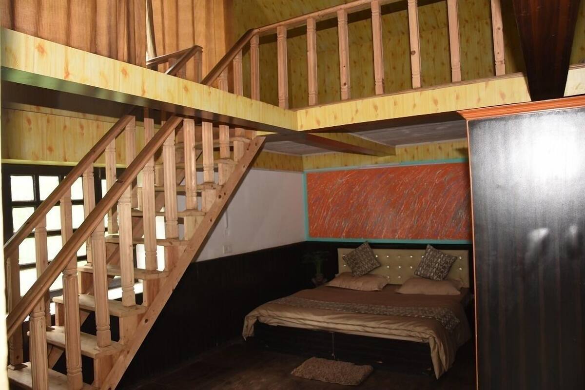 A bedroom with a wooden staircase, a bed with a headboard, and a wardrobe.
