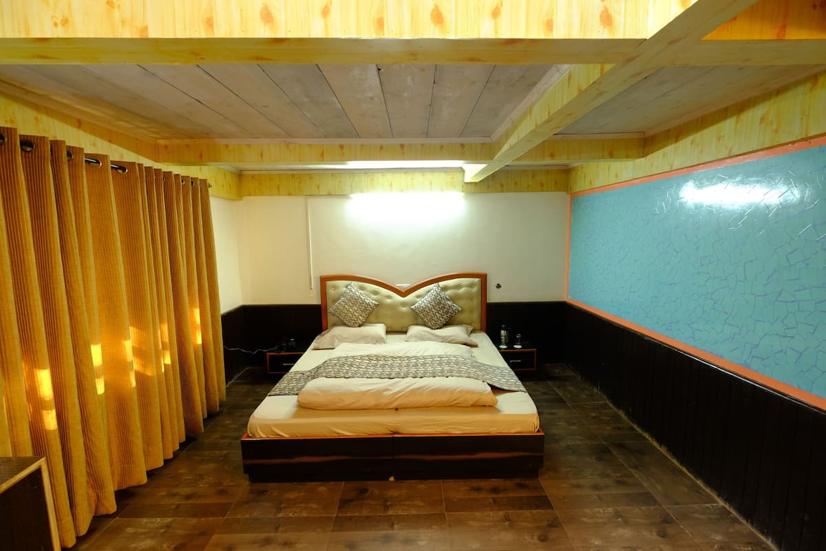A bedroom with a bed, curtains, a nightstand, and a wall with a geometric pattern.
