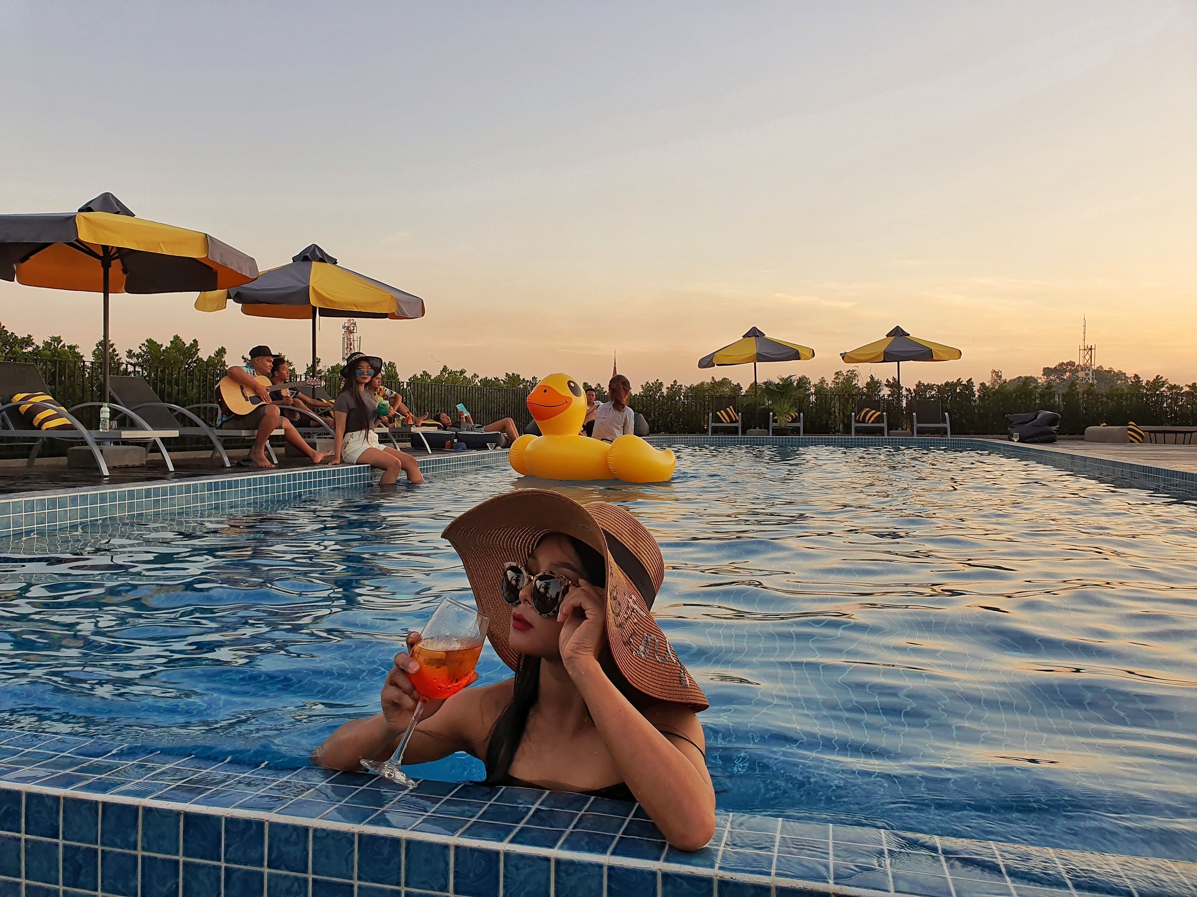 Una piscina con sillones de descanso y sombrillas.