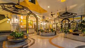 A spacious lobby with a modern design, featuring a central fountain, multiple seating areas, and decorative arches.