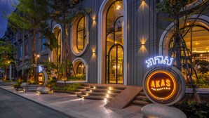 Un bâtiment moderne doté de grandes fenêtres en arc de cercle et d’une enseigne au néon indiquant la présence d’un bar au bord de la piscine.