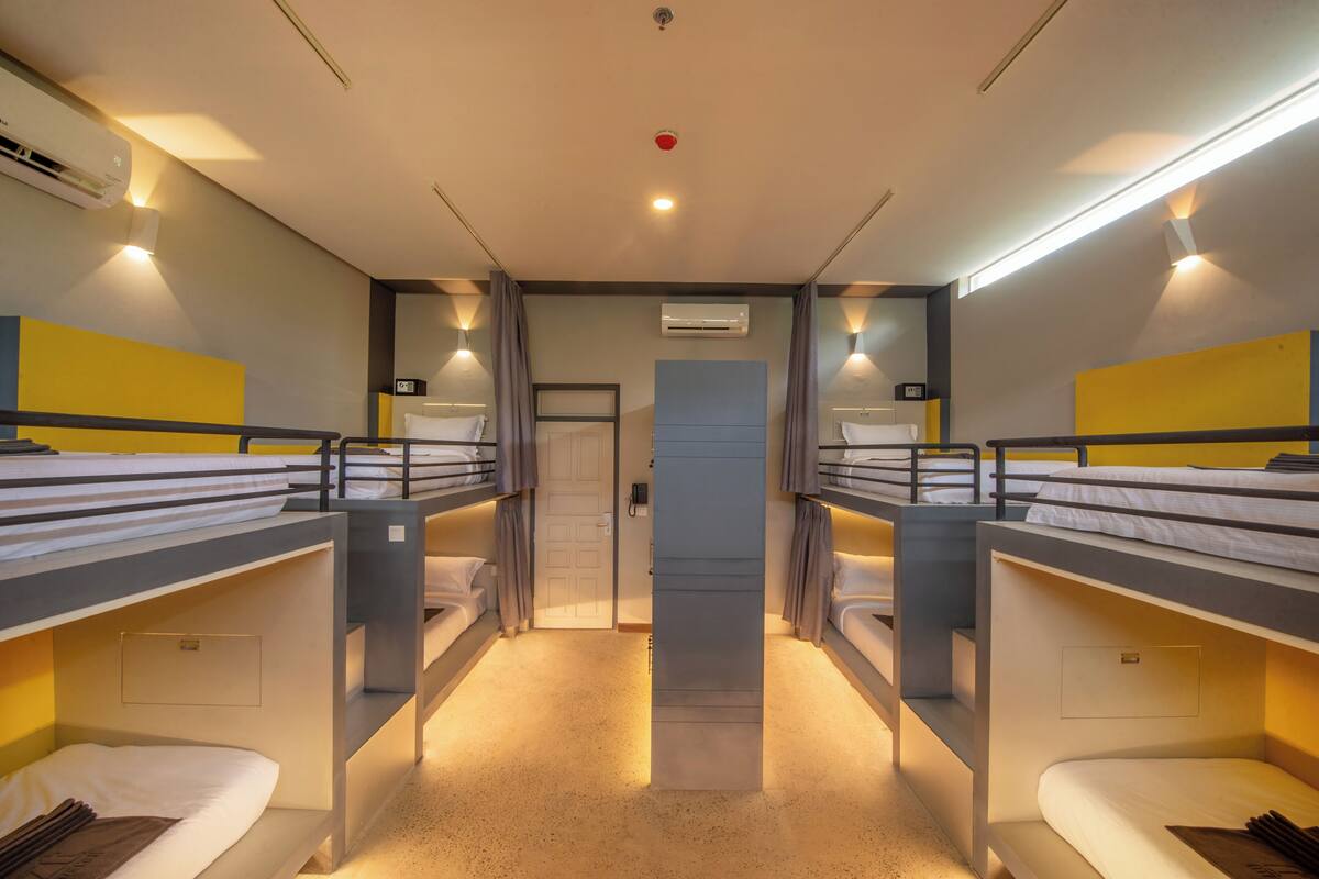 Une chambre avec deux lits superposés, une porte et un appareil de climatisation.