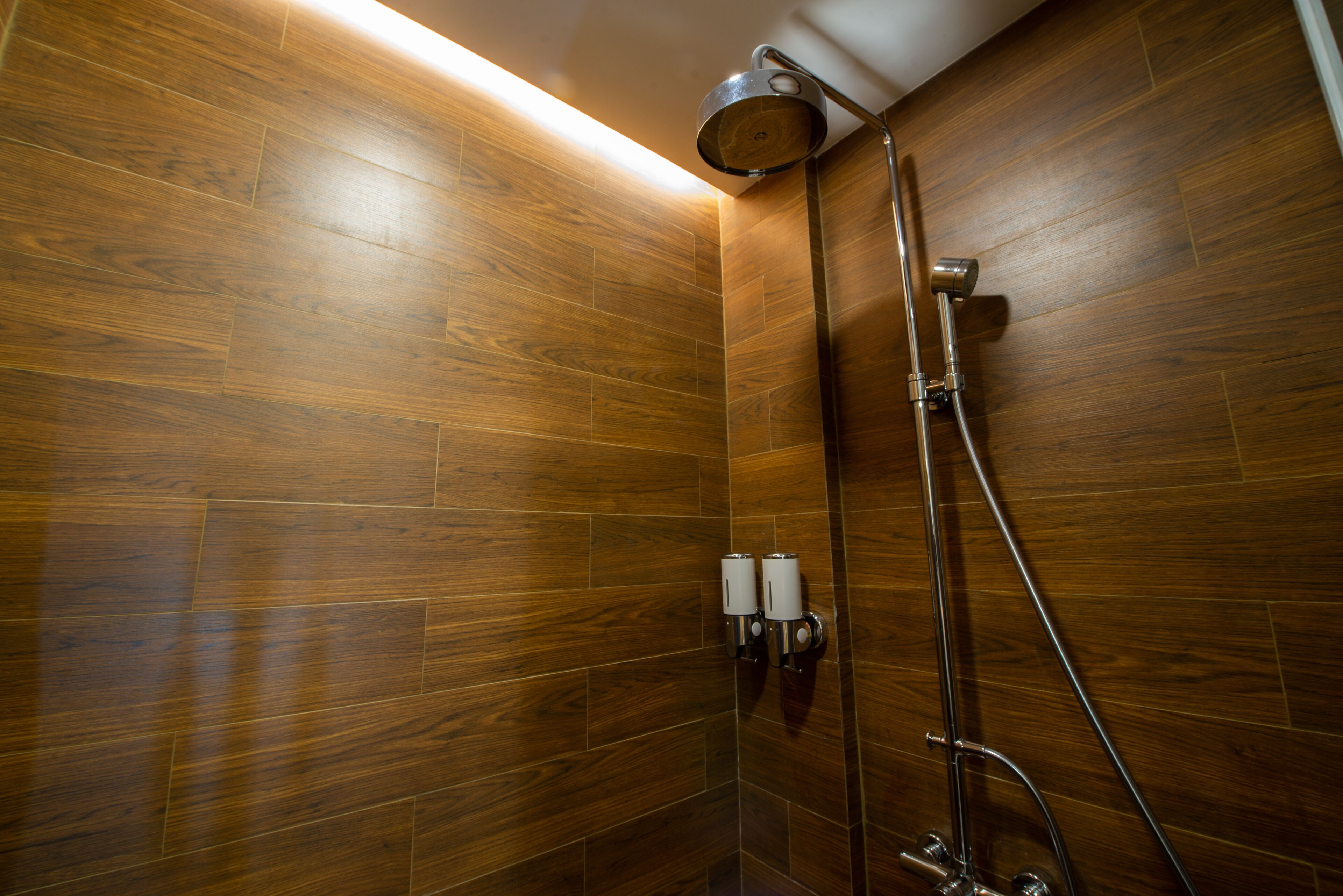 A shower area with wooden walls and a metal showerhead.