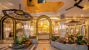 A grand lobby with a central fountain, ornate arches, and a ceiling fan.