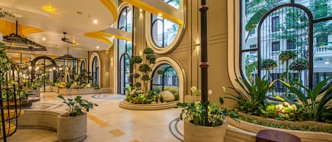 Un lobby amplio con ventanas grandes, macetas circulares con vegetación y un diseño de techo moderno.