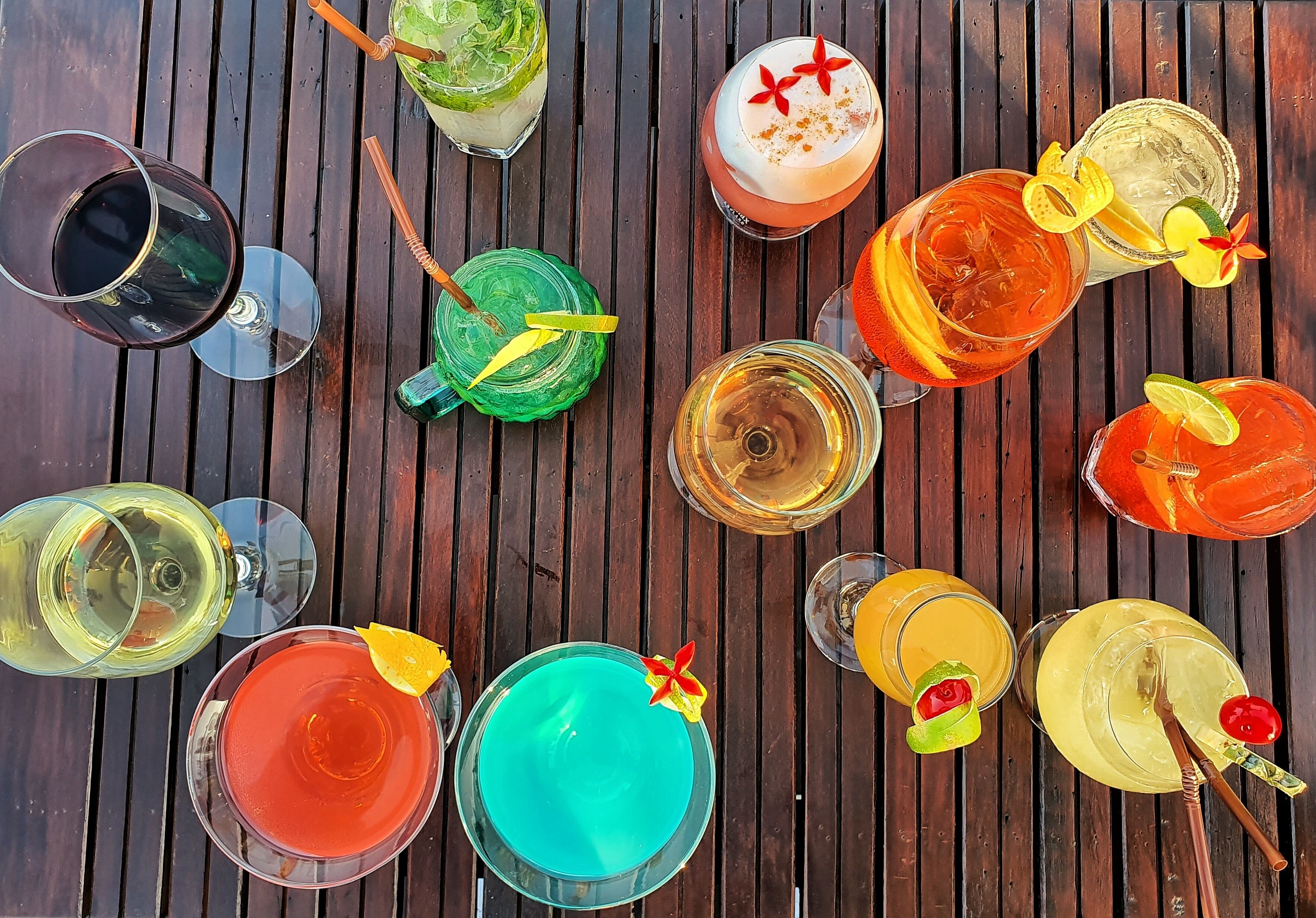 A variety of colorful cocktails on a wooden table.