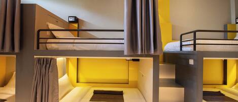A bunk bed room with a control panel on the wall, curtains, and a bed with a blanket.