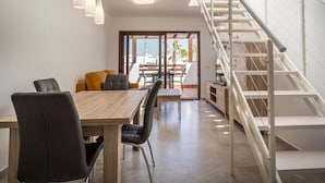 A modern kitchen with a wooden table and chairs, a staircase, and a view of the outdoors. - Apartamento Pimienta  (Mar de Pulpi) (San Juan de los terreros)