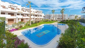 A swimming pool with a logo, surrounded by greenery and white buildings. - Apartamento Pimienta  (Mar de Pulpi) (San Juan de los terreros)