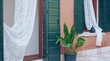 A building with green shutters, a potted plant, and a tiled floor.
