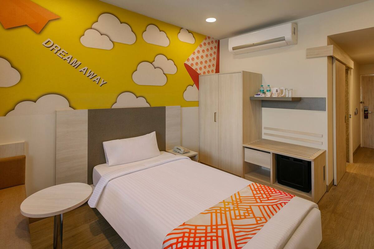 Quarto de hotel com uma cama, mesa de cabeceira e um guarda-roupa.