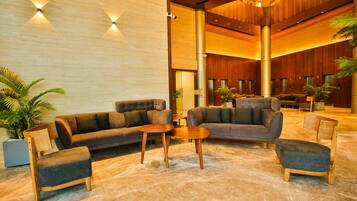 A spacious lobby with a modern design, featuring sofas, armchairs, and a coffee table.