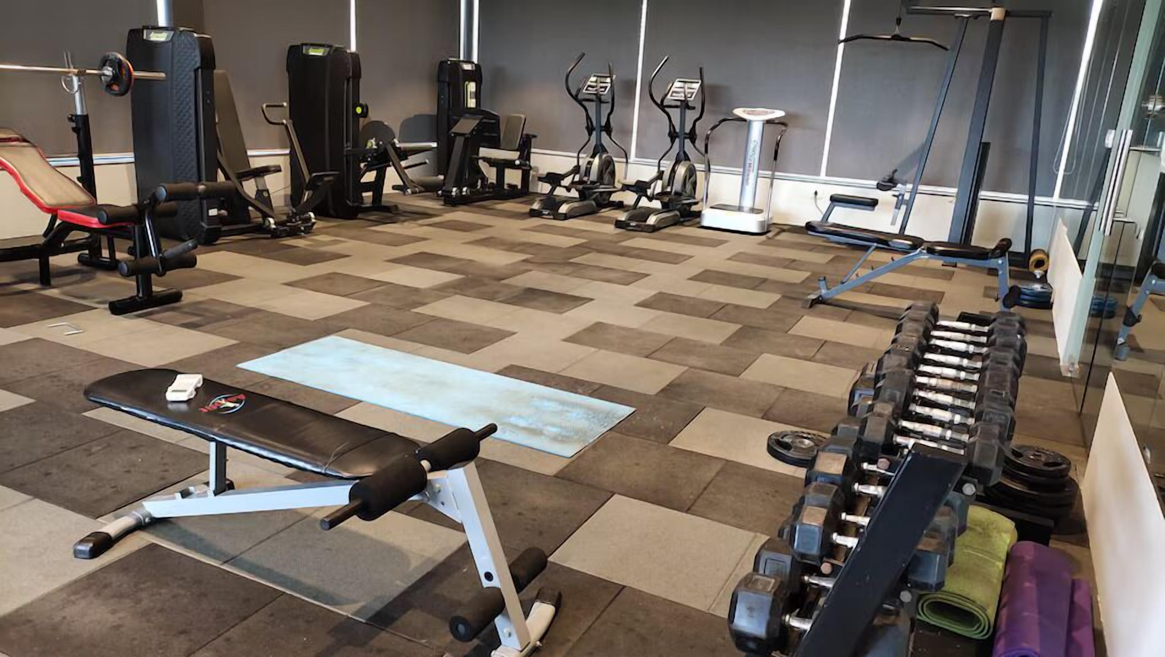 A gym with various exercise equipment including treadmills, elliptical machines, and free weights.
