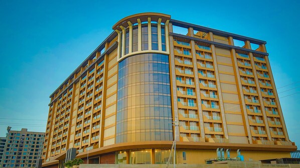 A high-rise hotel with a curved glass facade, multiple balconies, and a modern architectural design.
