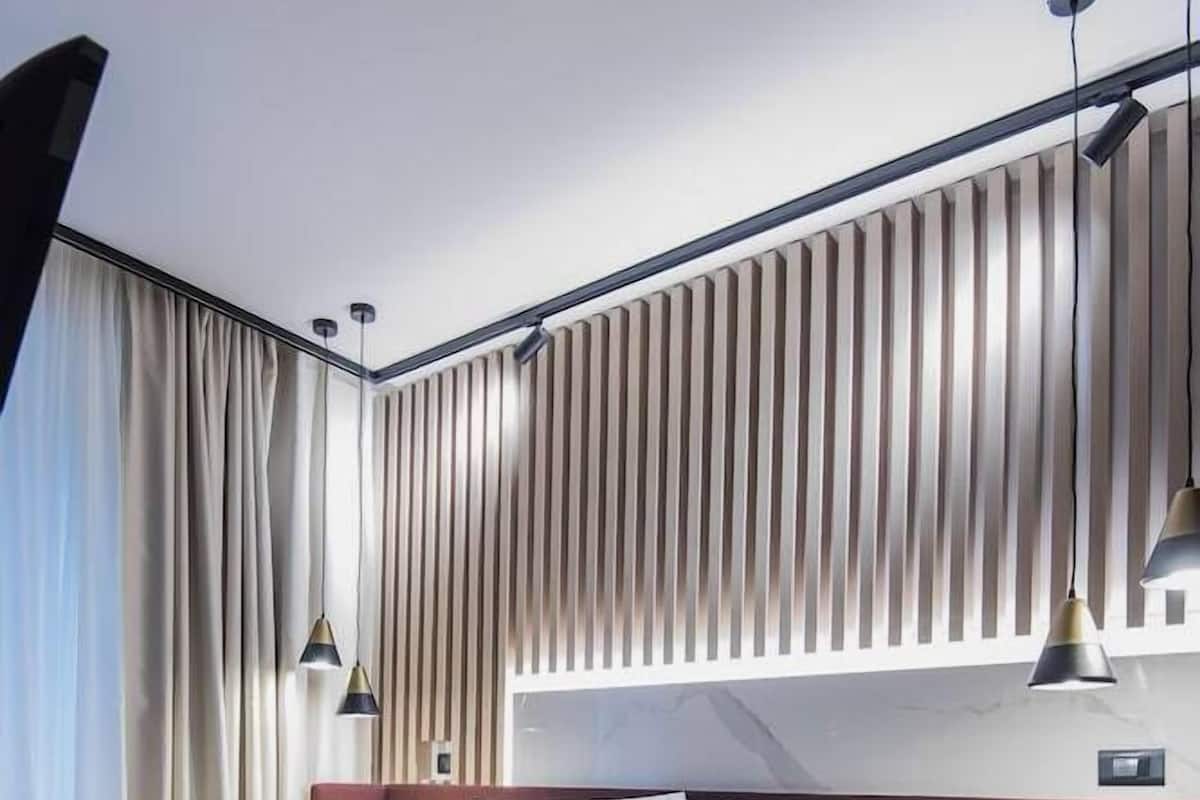 A modern hotel room with a large bed, a bedside table, and a wall-mounted light fixture.