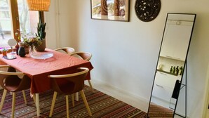 A dining area with a table set for four, a mirror, and a potted plant. - Large artsy apartment in Pasila (Helsinki)