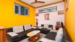 A living room with a sofa set, a coffee table, a television, and a ceiling fan. - Pacific Guest House (Kathmandu)