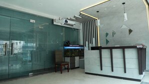 A reception area with a glass wall, an air conditioning unit, a fish tank, and a desk with a chair.