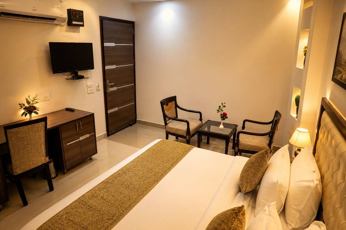 Una habitación de hotel con cama, escritorio, silla, televisor y puerta.