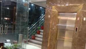 An interior with a reception desk, a glass wall, a staircase, and an elevator.