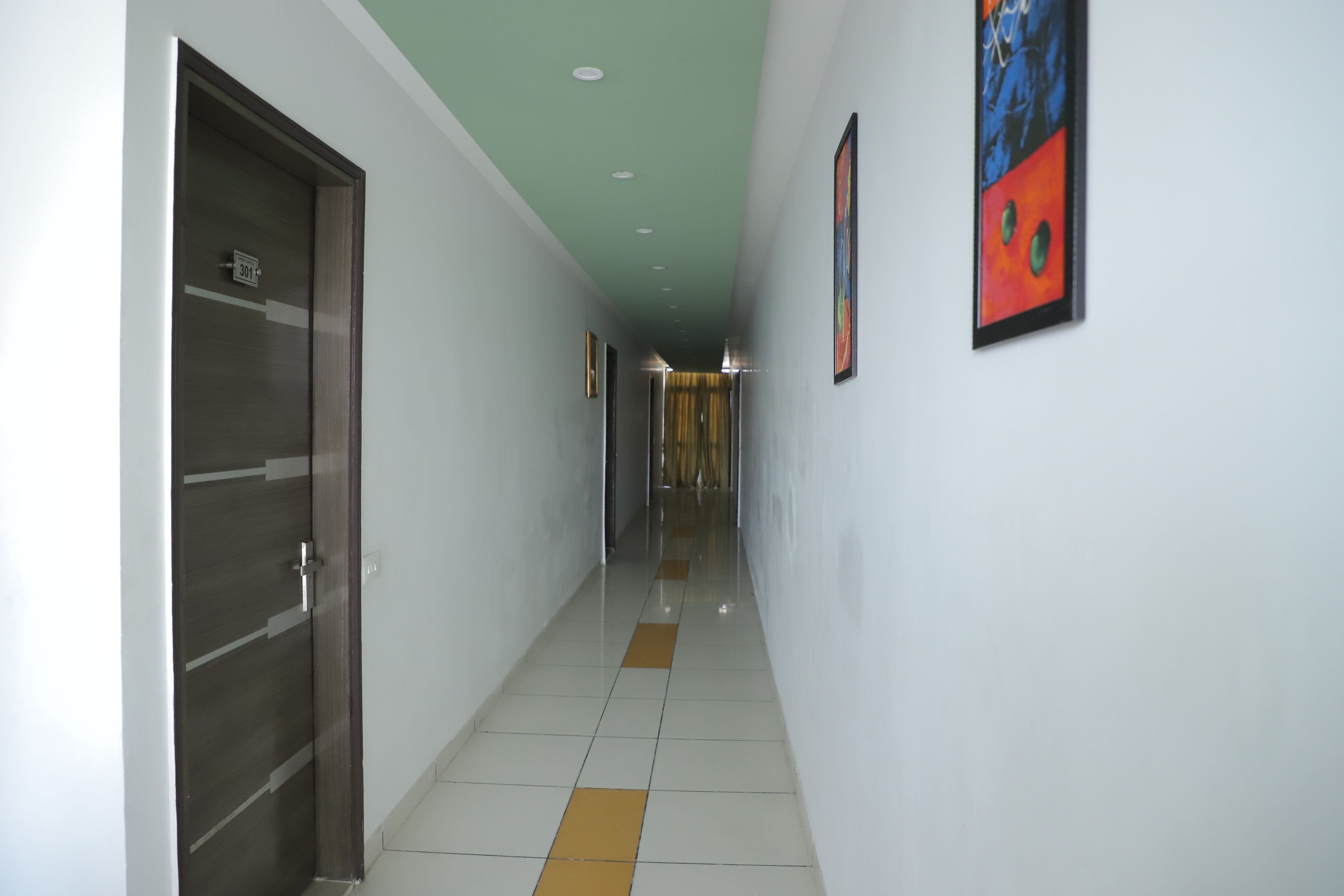 A hallway with a door labeled "301", a tiled floor with orange and white tiles, and a ceiling with recessed lighting.