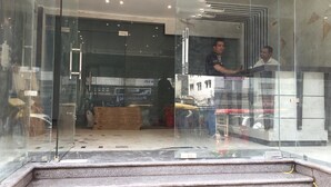 A hotel entrance with a glass door, a staircase leading inside, and a reflection of two people inside.