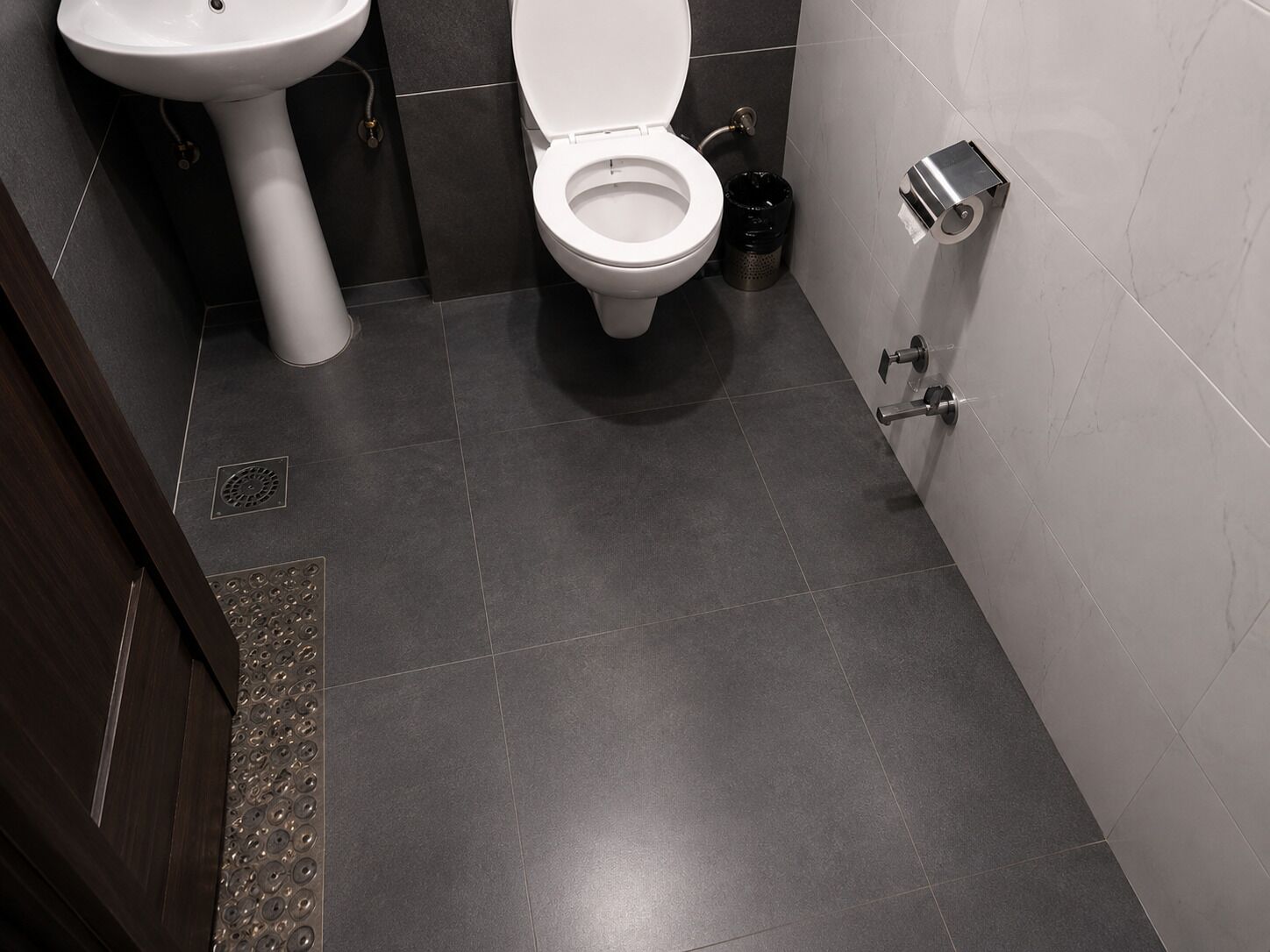 Une salle de bain équipée de toilettes, d’un lavabo et d’une poubelle.