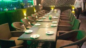 A restaurant with multiple tables and wicker chairs, some with plates and cutlery.