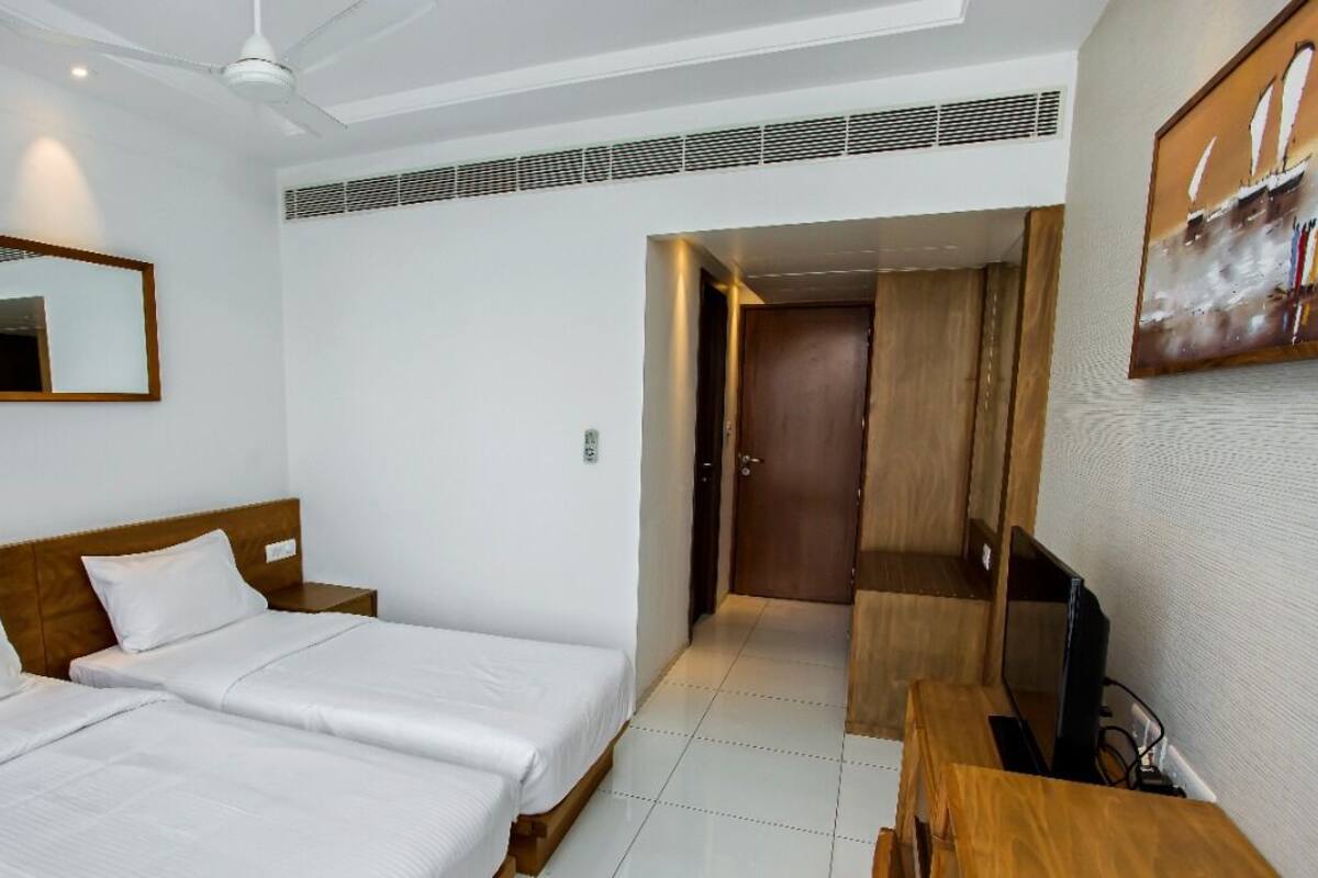 Habitación de hotel con dos camas, un televisor y un cuadro en la pared.