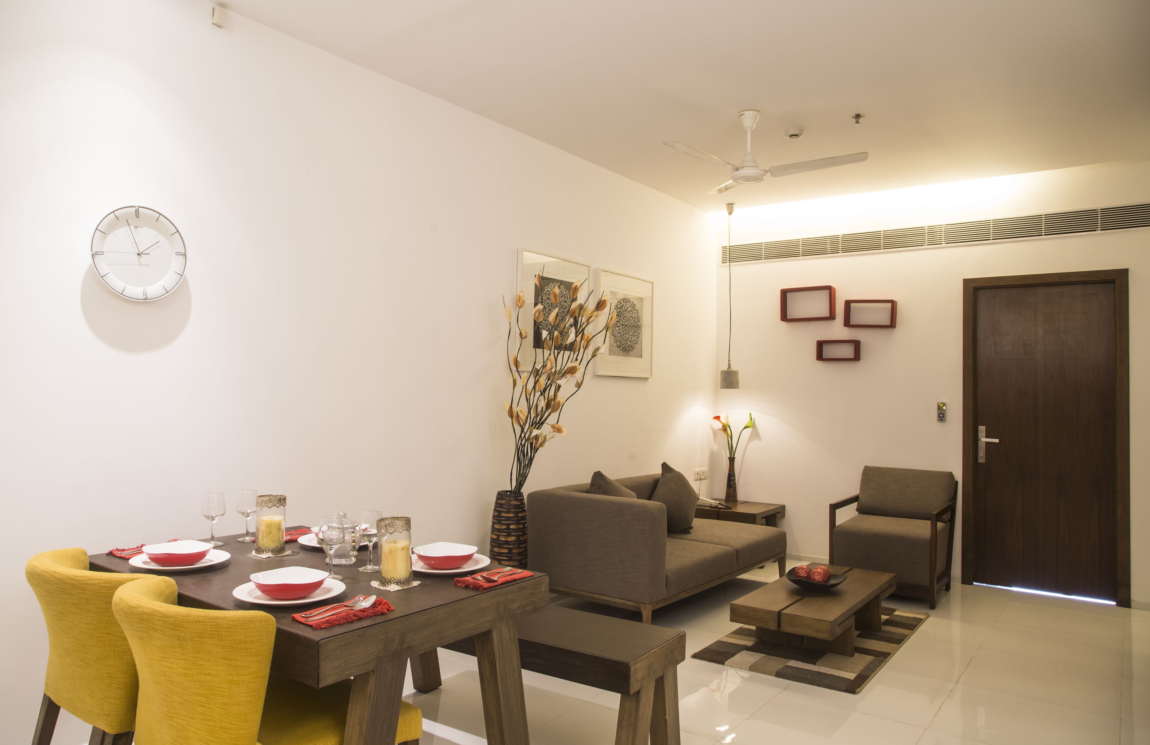A modern living room with a dining area, featuring a sofa, chairs, a coffee table, and a dining table set for four.