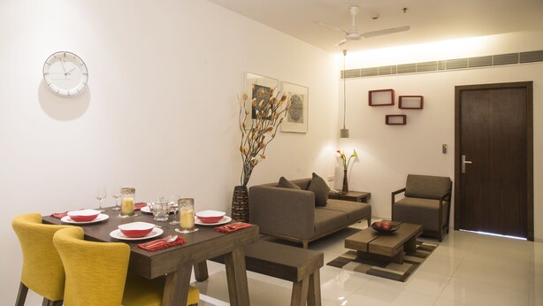 A modern living room with a dining area, featuring a sofa, chairs, a coffee table, and a dining table set for four.