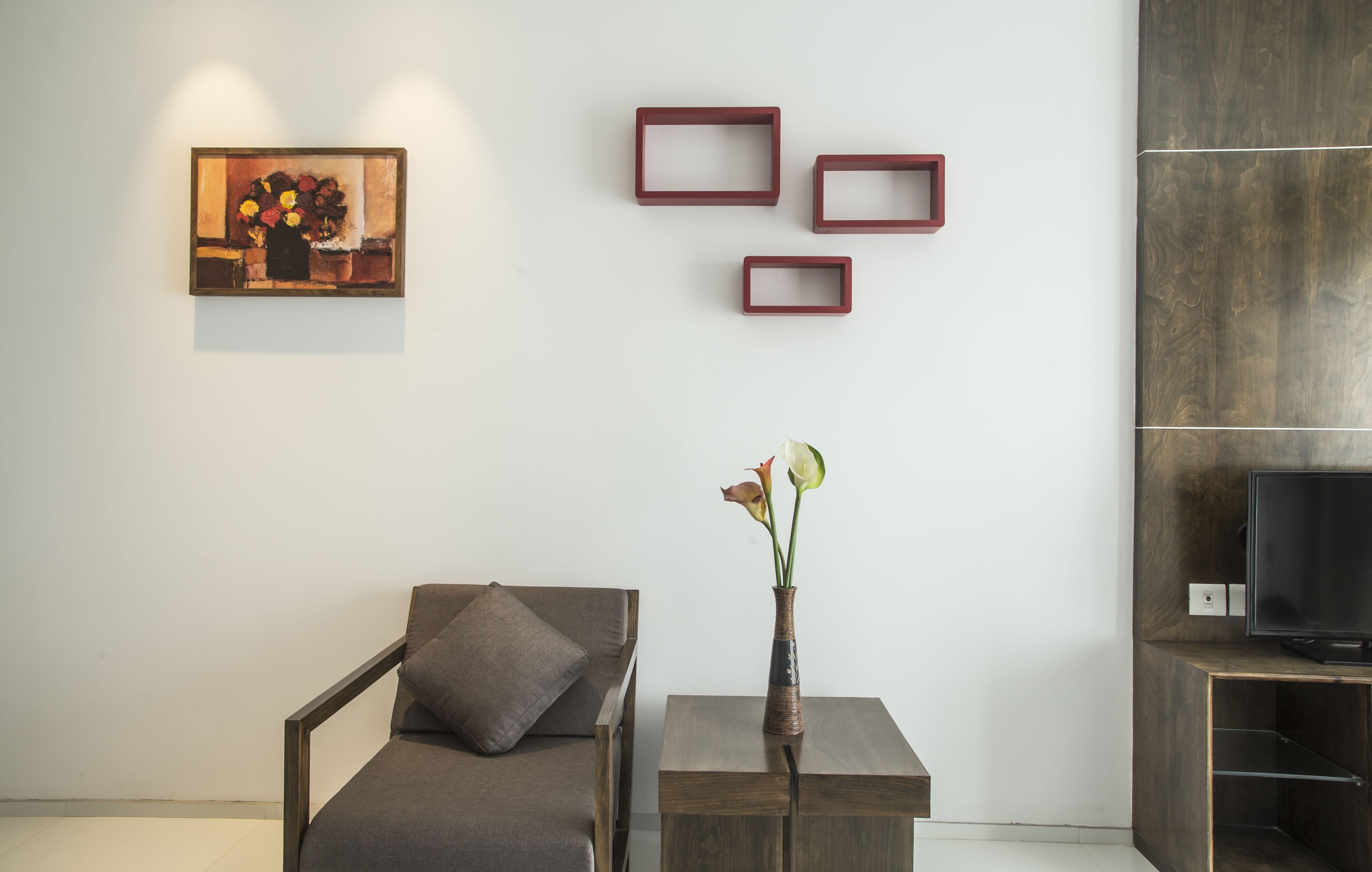 A modern living room with a sofa, a small table with a vase, and a flat-screen TV on a wooden stand.